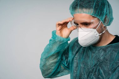 COVID-19 Koronavirüs salgını, adam doktor gözlük takıyor, maske takıyor, gözlük takıyor, lateks eldiven takıyor ve virüse karşı koruyucu giysiler giyiyor.