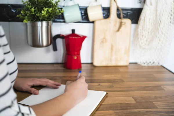 Frau Schreibt Einem Notizbuch Auf Einem Holztisch Ihrer Heimischen Küche — Stockfoto