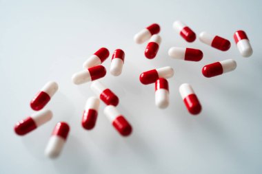Birçok kırmızı ve beyaz kapsül hapları gölgeli beyaz arka plana yayıldı. Küresel sağlık hizmeti kavramı. Antibiyotik ilaç direnci. Antimikrobik kapsül hapları. İlaç endüstrisi.. 