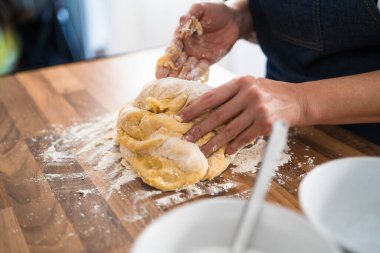 Dişi eller, un serpiştirilmiş ahşap bir masada tatlı bir pasta için hamuru yoğurur. Evde, mutfakta pasta yapıyorum..