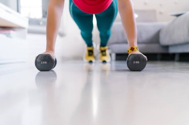 Kadın evinde halterle şınav çekiyor.