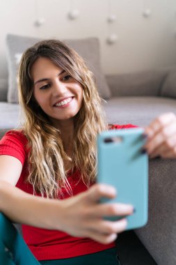 Mutlu kadın evde akıllı telefon kullanarak gülümsüyor.