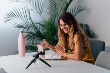 Kadın akıllı telefonuyla evde video görüşmesi yapıyor..