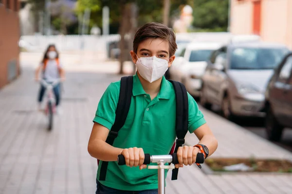 Jongen en meisje dragen maskers en rijden op een scooter en fiets op straat — Stockfoto