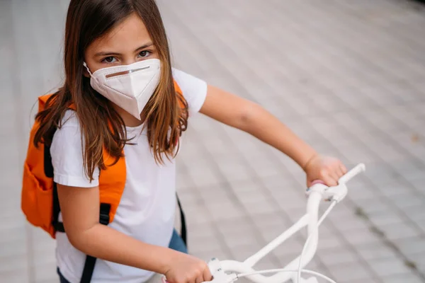 Meisje met gezichtsmasker fietst op straat tijdens de coronavirus pandemie — Stockfoto