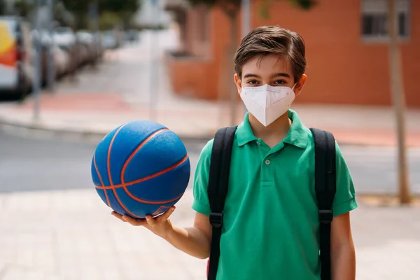 Jongen draagt masker met een basketbal om op straat te spelen in de pandemie — Stockfoto