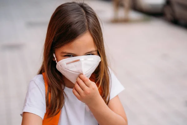 Klein meisje met masker in een park tijdens de coronavirus pandemie — Stockfoto