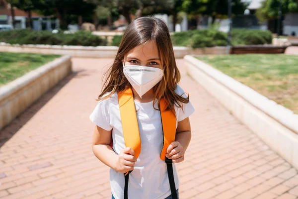 Klein meisje met masker in een park tijdens de coronavirus pandemie — Stockfoto