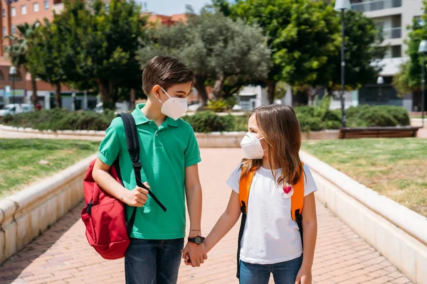 Jongen en meisje met rugzakken en maskers gaan naar school in coronavirus pandemie — Stockfoto