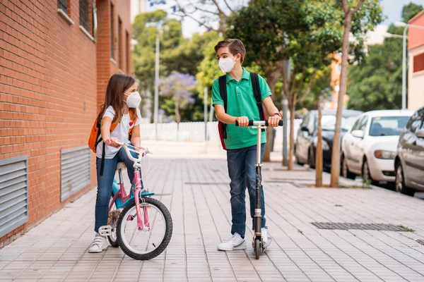 Niño y niña usando máscaras y montando una moto y bicicleta en la calle —  Fotos de Stock