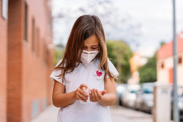 Klein meisje met masker desinfecteert haar handen met hydroalcoholische gel. — Stockfoto
