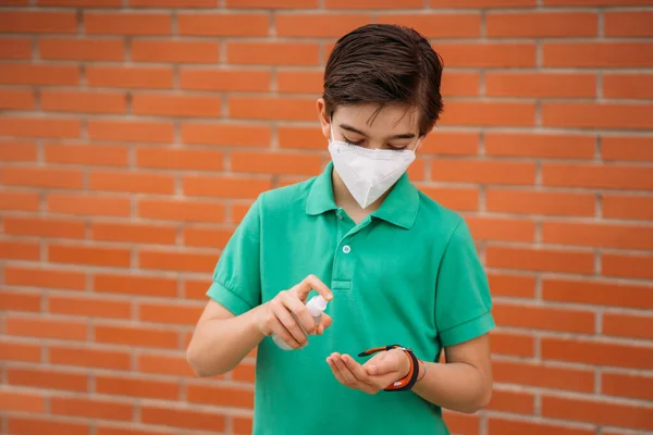 Jongen met masker desinfecteert haar handen met hydroalcoholische gel. Coronavirus. — Stockfoto