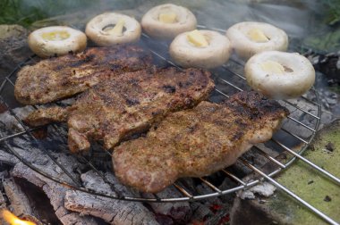 Et ve mantarlar barbekü ateşinde kızarıyor.