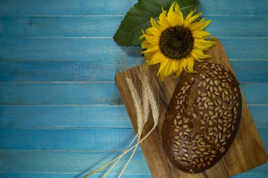 Mavi ahşap masada ayçiçekli ekmek.
