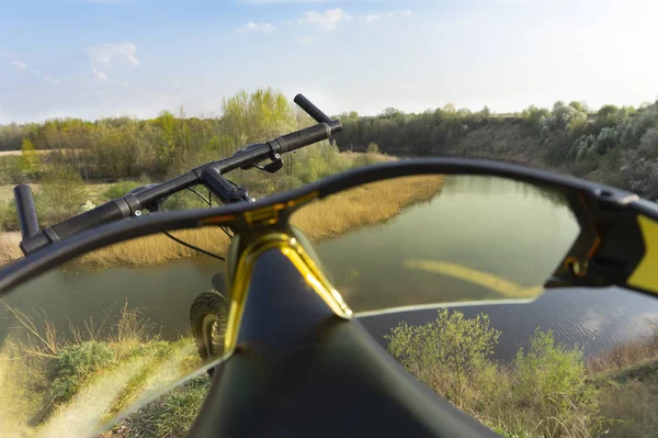 Jezdecké brýle na sedadle kola s výhledem na řeku — Stock fotografie