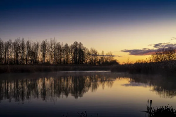 Яркий оранжевый закат, отраженный в спокойном озере — стоковое фото