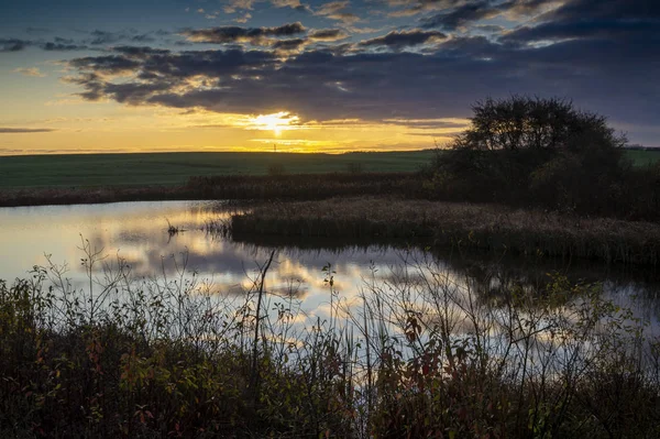 Vivid orange sunset reflected in a tranquil lake — Stock Photo, Image