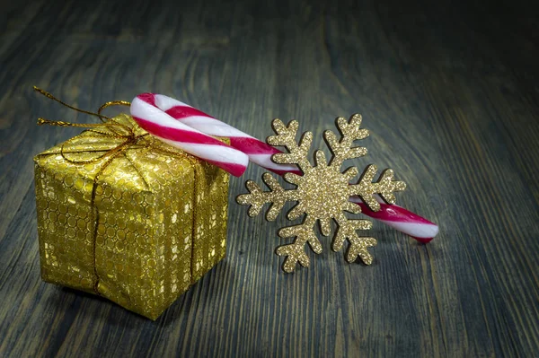 Goud verpakt cadeau, suikerriet en een sneeuwvlok — Stockfoto