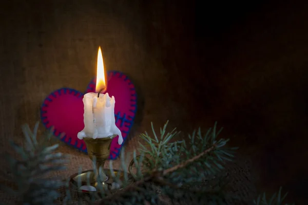 Горящая свеча и маленькое игрушечное сердце — стоковое фото