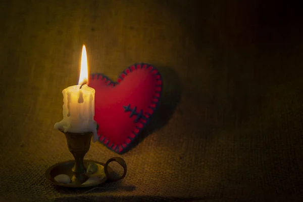 Палаюча свічка і маленьке іграшкове серце — стокове фото