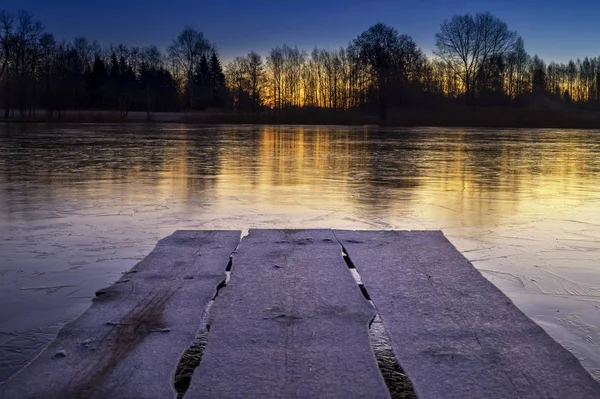 Rustic wooden jetty on a frozen lake at sunset — Stock Photo, Image