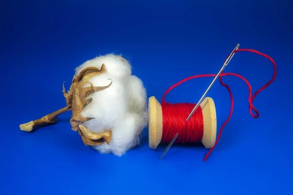 Boll de algodão com carretel de fio vermelho brilhante — Fotografia de Stock
