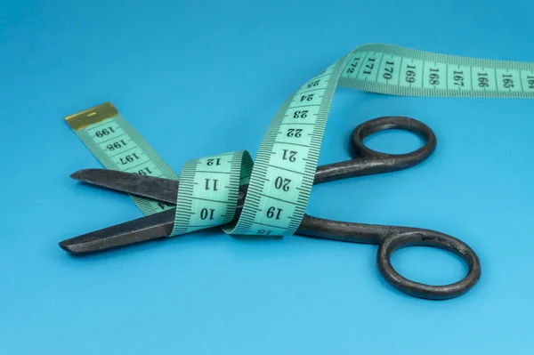 Metal scissors wrapped around with tape measure — Stock Photo, Image