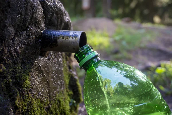 Filling a green plastic water bottle at a fountain