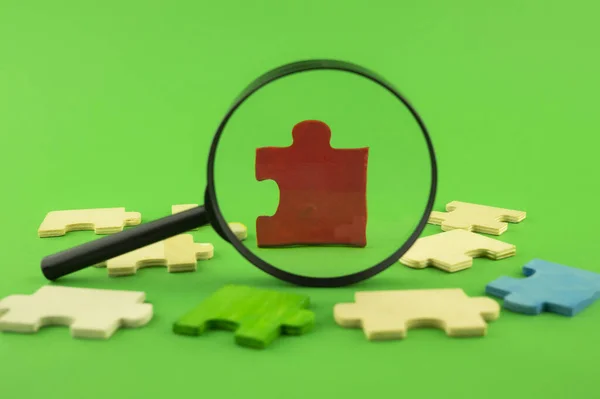 Colorful puzzle pieces with magnifying glass — Stock Photo, Image