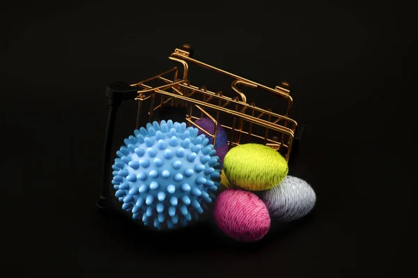 Blue virus molecule, shopping cart and creative colorful eggs made from yarn conceptual of the possibility of infection with corona virus or Covid-19 over a black background