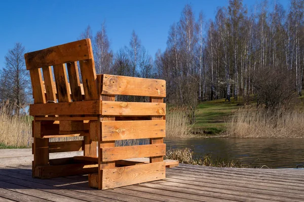 用木制甲板上的木板做的粗糙的手工制作的椅子 可以俯瞰春日阳光下芦苇覆盖的河流或湖泊 — 图库照片