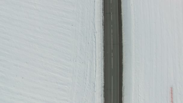 Дорога в заснеженном зимнем поле с автомобилями и грузовиками. Вертикальный воздушный статический выстрел . — стоковое видео