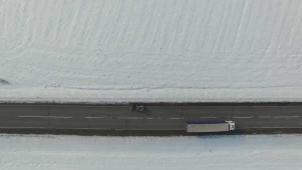 Déneigement mashine nettoie une route dans un champ d'hiver enneigé avec des voitures et des camions. Plan vertical aérien . — Video