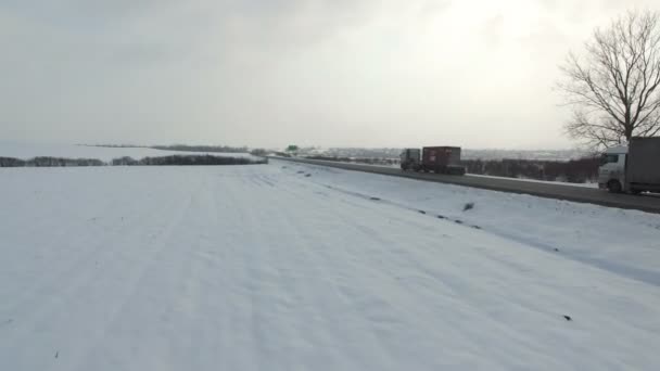 Aerial shot of truck driving winter road in snowy field. — Stock Video