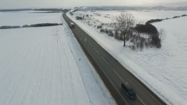 Aerial shot of truck and cars driving winter road in snowy field. — Stock Video