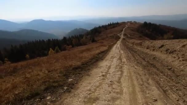 Ponto de vista traseiro: SUV com turistas na estrada de terra através da estrada rural até a montanha . — Vídeo de Stock