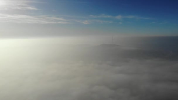 Flying over clouds. Video shot by drone in early morning. Smog above city. Look at the city television tower. Real time footage. — Stock Video