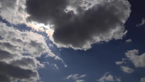 Hermoso lapso de tiempo 4K. Los rayos del sol rompen a través de nubes esponjosas blancas en el cielo azul vivo — Vídeo de stock