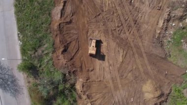 İnşaat alanında buldozer sürüşünün en üst hava görüntüsü. 4K atış.