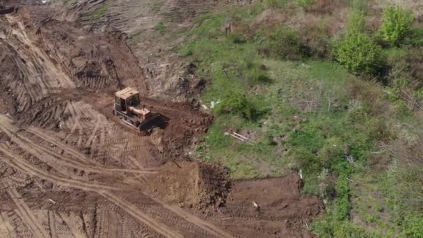 Aerial view of bulldozer flattening surface on further construction site — Stock Video