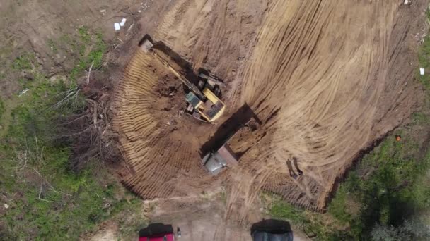 Luftaufnahme: Gelber Bagger schüttet Erde in Kipper. — Stockvideo