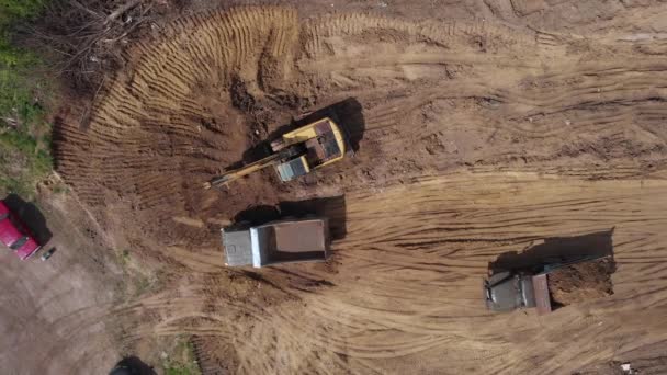 공중 위에서 본 광경: 오리발 굴착기가 오리발에 흙을 부어넣는 모습. — 비디오