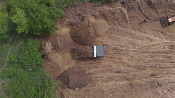 顶层空中射击：倾卸者在原地倾泻泥土，准备建造住宅. — 图库视频影像