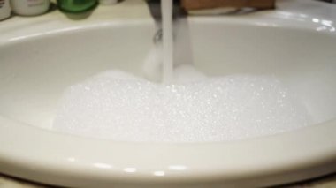 Su musluk sızdırılmış ve lavaboya kalın sabun köpüğü ile doldurur