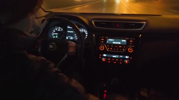 Una mujer está conduciendo un coche a través de la ciudad nocturna, y responde a una llamada telefónica entrante — Vídeo de stock