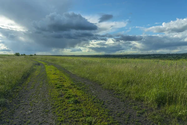 Chemin de terre à travers le champ sur le fond de nuages de pluie — Photo