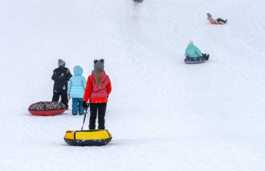Renkli giysili çocuklar şişme yüzüklerle kayarak kayıyorlar.