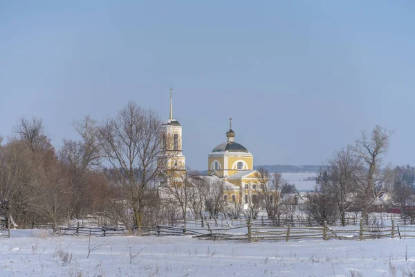 Winterdörfliche Landschaft mit Kirche, die Sonne scheint Schneeverwehungen — Stockfoto