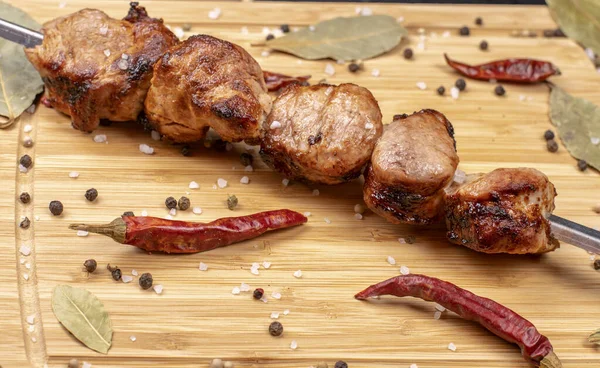 Barbacoa cocida en un pincho está en el tablero espolvoreado con chile, pimienta negra y sal —  Fotos de Stock