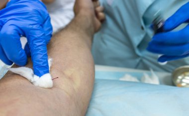 Mavi eldivenli bir tıp çalışanının elleri test için damardan kan alır.